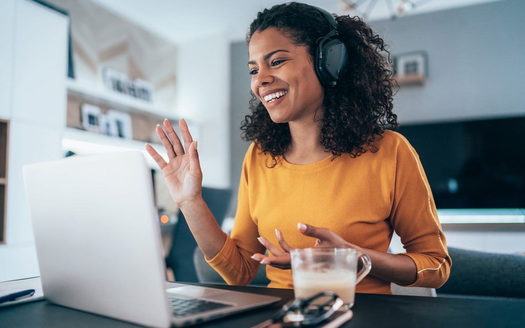 Smiling woman wearing a headset waving during a video call