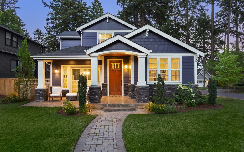 Suburban home with warm lights on at dusk