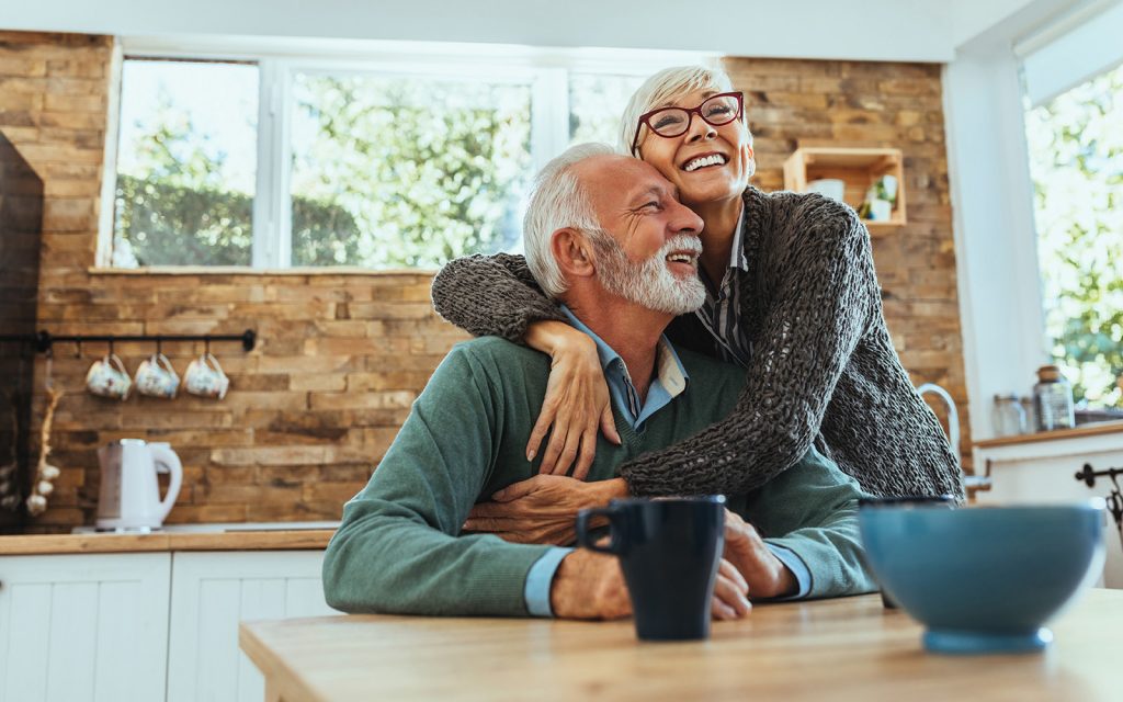 Older couple smiling and embracing in their kitchen