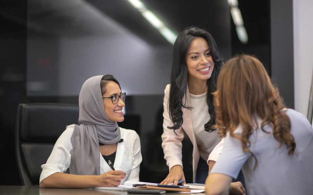 Three colleagues talking and smiling at a table