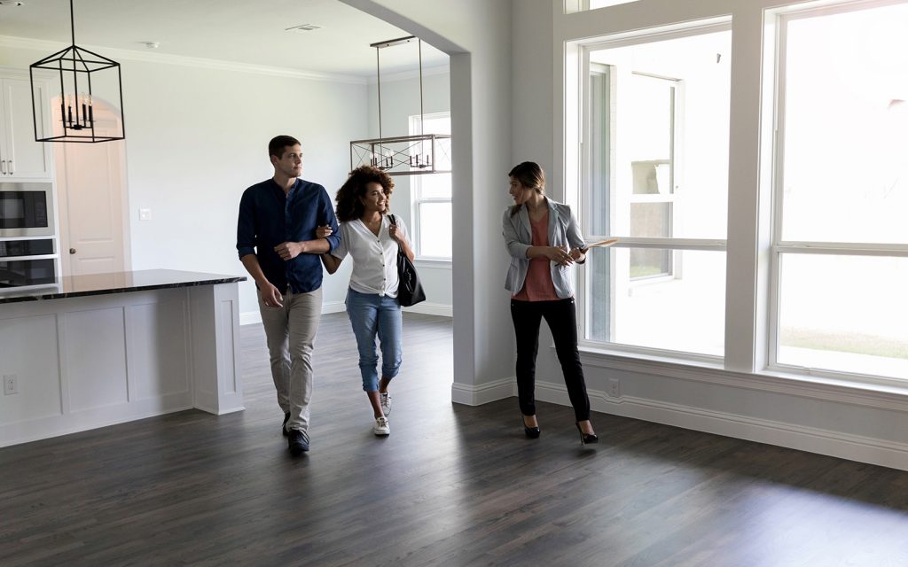 Family walking through an empty new home with a real estate agent
