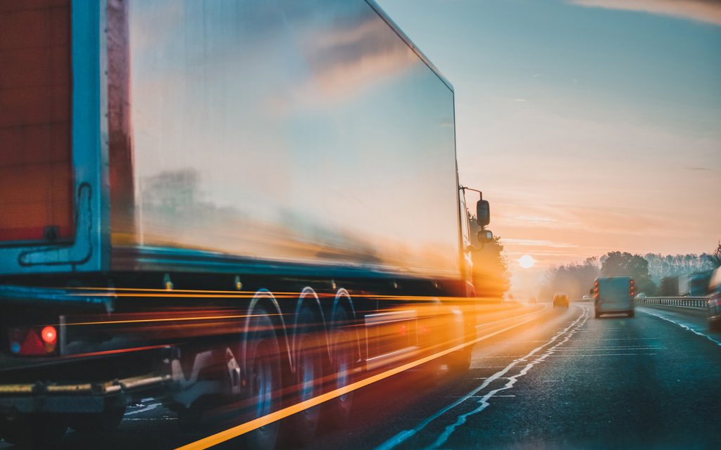 Moving truck driving on a highway at sunset