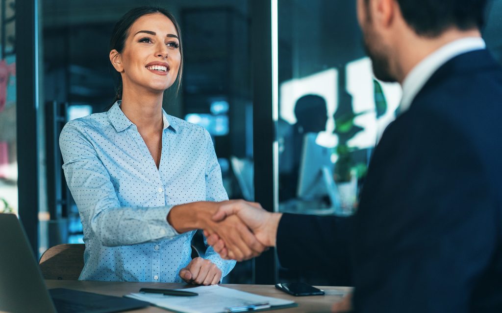 Woman shaking hands with a client across a desk