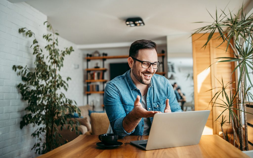 Man smiling and gesturing while on a video call at his laptop