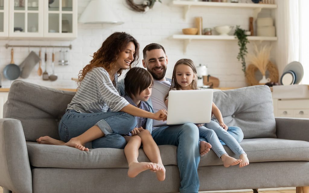 Family sitting together on a sofa looking at a laptop