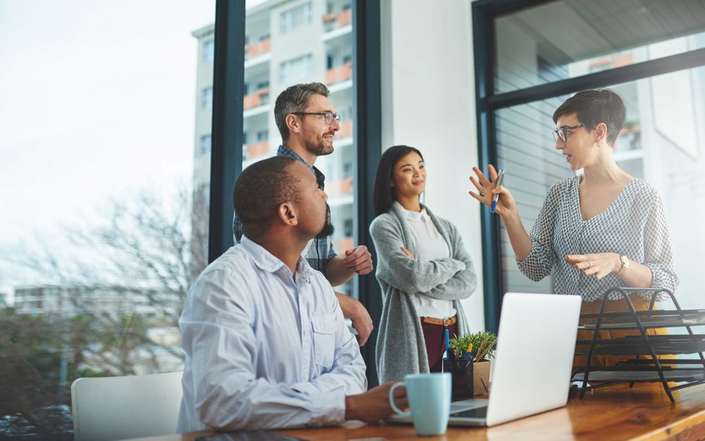 Colleagues talking in an office next to a laptop