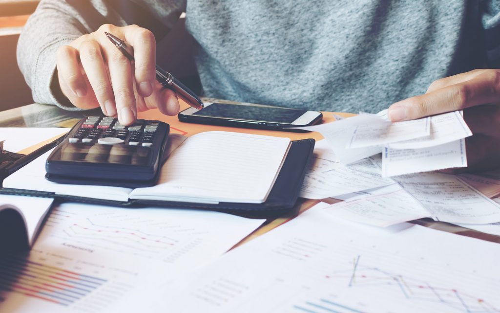 Person using a calculator while reviewing financial paperwork