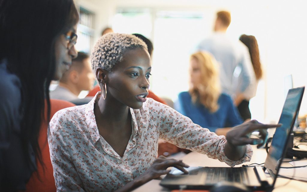 Woman working at a laptop in a busy office