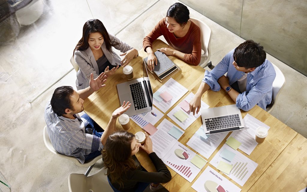Overhead view of colleagues reviewing charts and laptops at a table