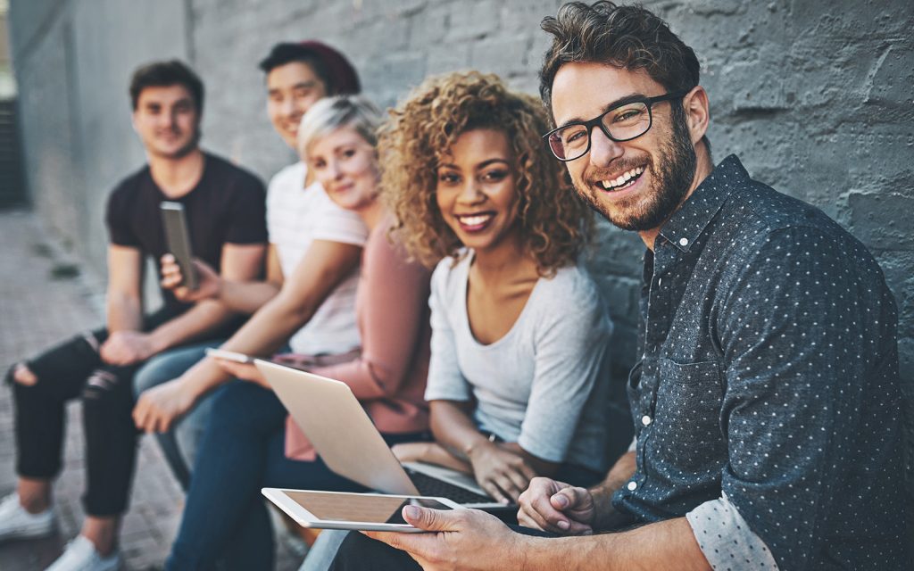 Group of friends smiling and looking at a tablet