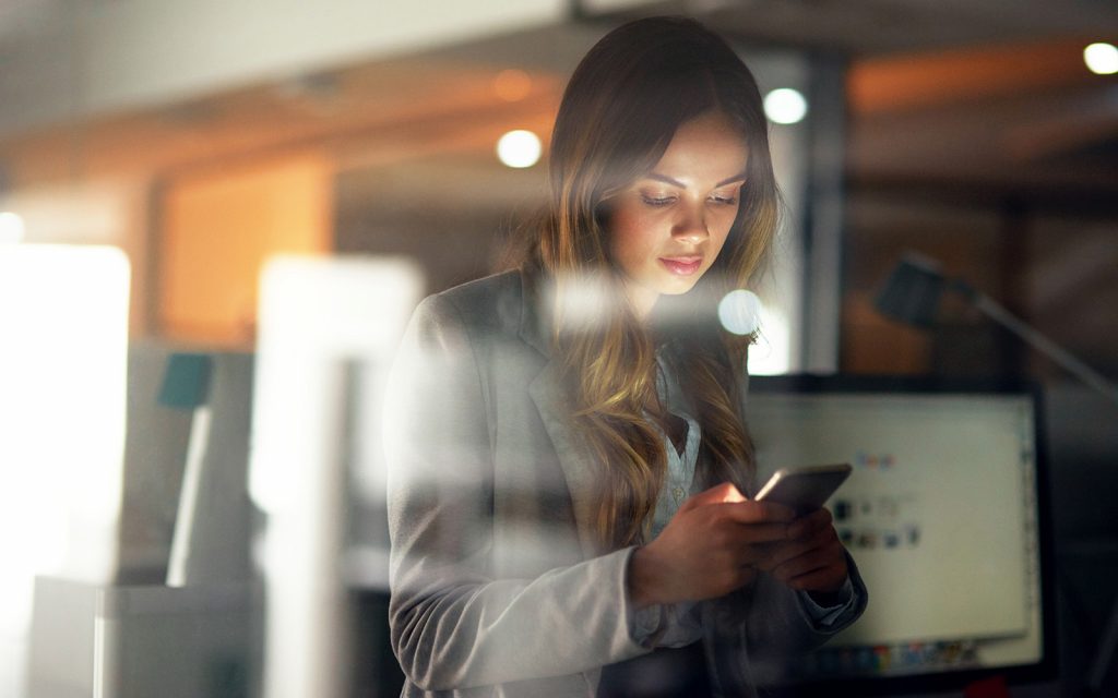 Woman checking her phone in a dimly lit office