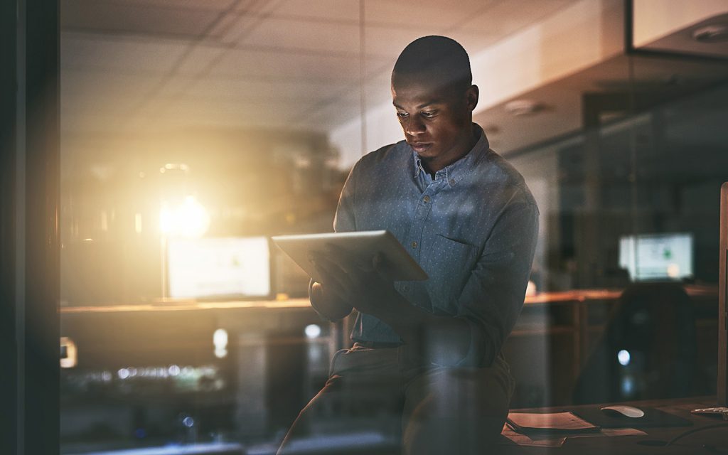 Man working on a tablet in an office at night