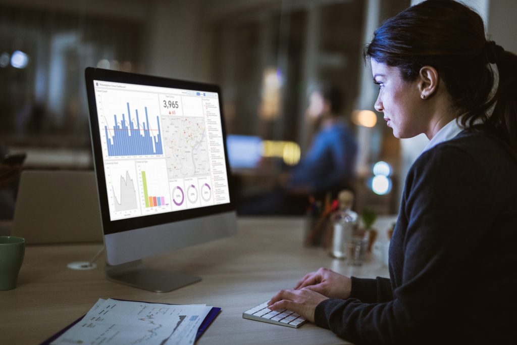 Woman reviewing analytics dashboards on a desktop monitor