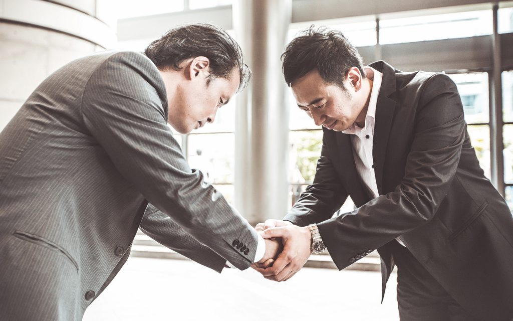 Two business people bowing and shaking hands