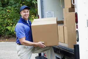 delivery man lifting cardboard boxes from the back of his truck